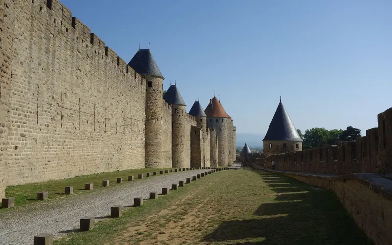 Remparts et tours à toits coniques de la cité médiévale de Carcassonne, entre les deux enceintes, sous un ciel bleu