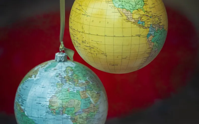 Deux boules de Noël en forme de globe terrestre, l'une tournée vers les Amériques, l'autre vers l'Afrique et l'Europe, suspendues à des rubans verts