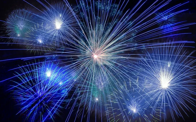 Feu d'artifice aux gerbes bleues et blanches qui éclatent dans le ciel nocturne