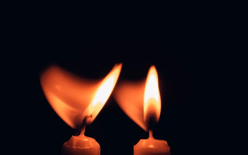 Deux bougies allumées dont les flammes vacillent dans l'obscurité